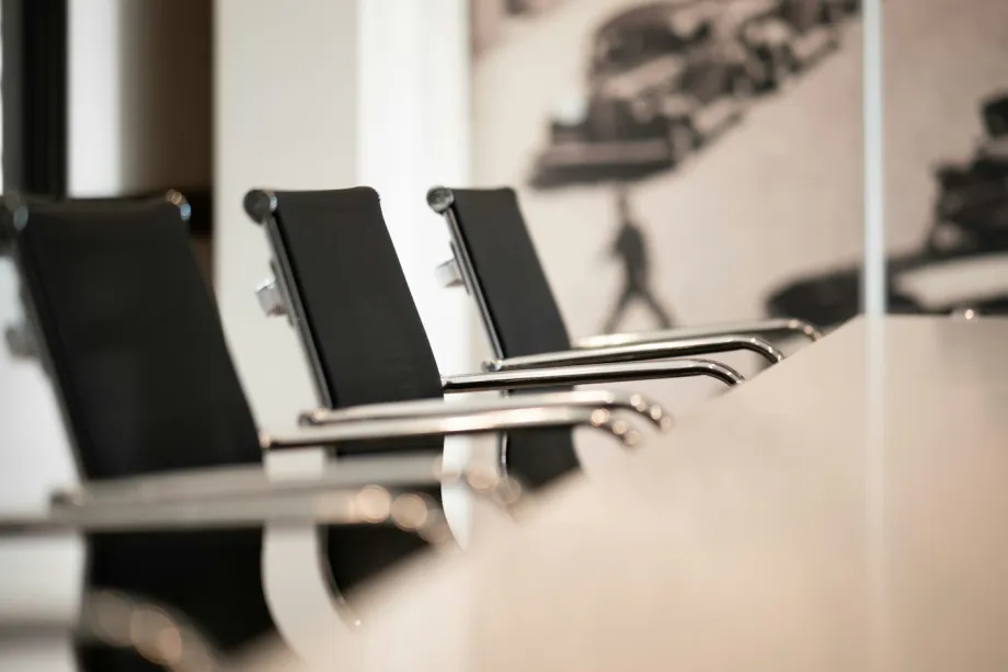 Row of black office chairs at an empty conference table