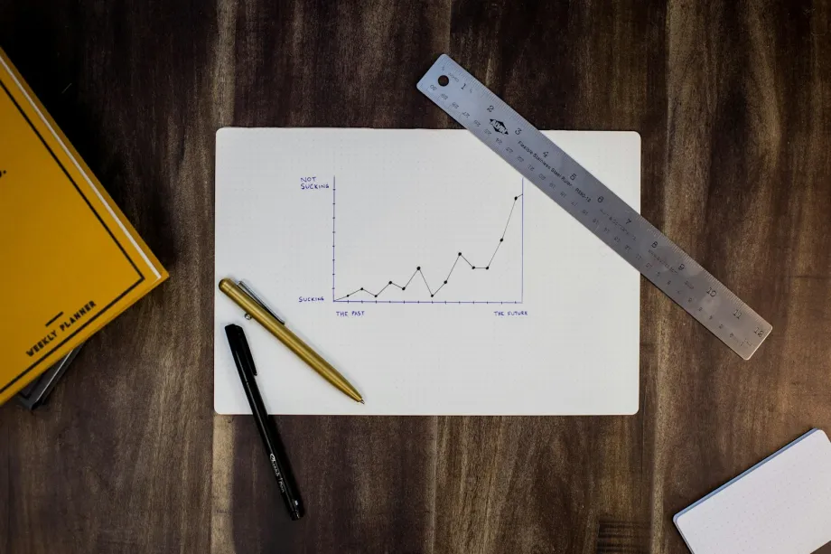 Hand-drawn line graph on paper with a metal ruler and two pens