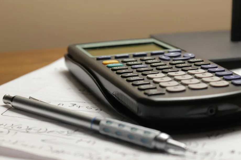 Calculator and pen lying on a sheet of paper